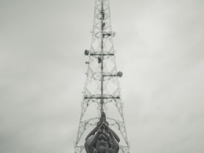 man in yellow jacket and black pants standing near white tower during daytime